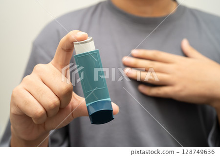 Asthma and chronic obstructive pulmonary disease COPD, Asian young man using metered dose inhaler MDI. 128749636