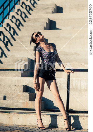 Near the wide steps, a charming girl with a long ponytail is sunbathing 128750700