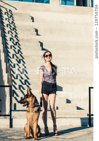 The young woman near the steps smiles as her four-legged friend sniffs the air 128750784