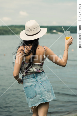 A young girl with a hat is sitting with her back turned A young girl with a hat is sitting with her back turned 128750794