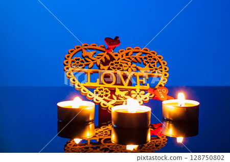Bright candles burn on a deep blue background, creating an atmosphere of peace and tenderness 128750802