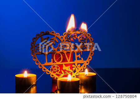 Lit candles on the deep blue backdrop create coziness and harmony Lit candles on the deep blue backdrop create coziness and harmony 128750804