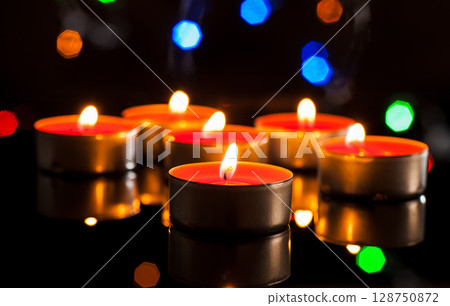 Dozens of candles shine like sparks of hope in the darkness 128750872