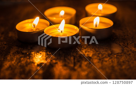 Candle flames flicker against the background of dark wood 128750897