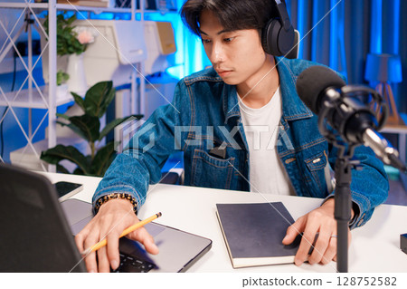 Podcaster writing notes while recording Podcaster writing notes while recording 128752582