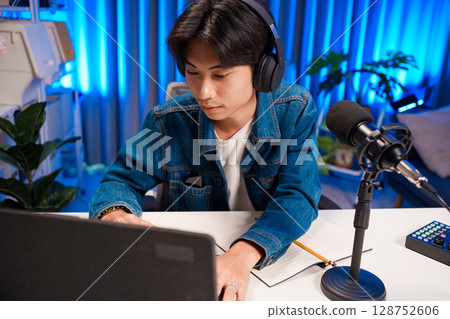 Smiling man podcaster make audio podcast with headphones and microphone in modern home studio. 128752606