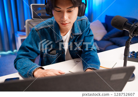 Smiling man podcaster make audio podcast with headphones and microphone in modern home studio. 128752607