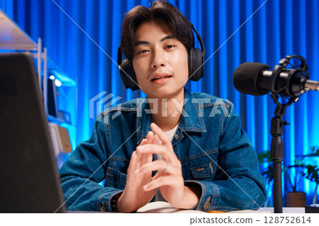 Smiling man podcaster make audio podcast with headphones and microphone in modern home studio. 128752614