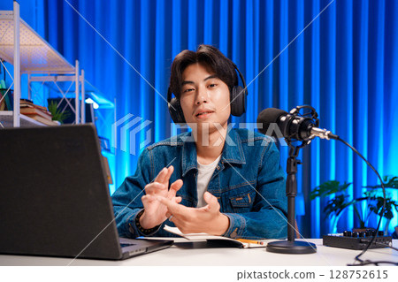 Smiling man podcaster make audio podcast with headphones and microphone in modern home studio. 128752615
