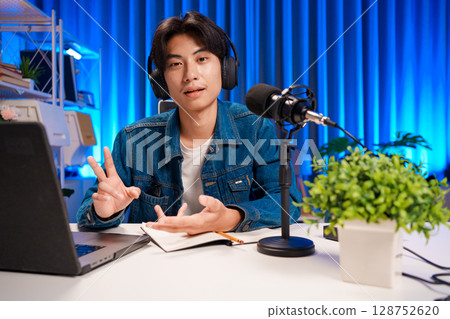 Smiling man podcaster make audio podcast with headphones and microphone in modern home studio. 128752620