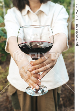 Woman Holding Glass of Red Wine in Vineyard Setting 128752934