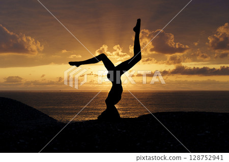 Yoga Silhouette at Sunset by the Sea. Mindfulness and Harmony 128752941