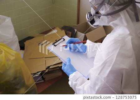 Workers in protective clothing at a garbage dump cleaning site 128753075