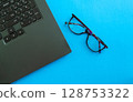 Desktop. Laptop and glasses on a blue background. 128753322