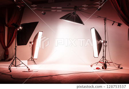 Red photo session studio. Professional sports background for advertisement. Workspace interior with grey backdrop, backstage and lamps Red photo session studio. Professional sports background for advertisement. Workspace interior with grey backdrop, backstage and lamps 128753537