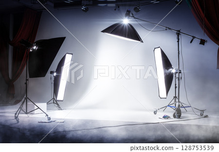 Photo session studio. Professional sports background for advertisement. Workspace interior with grey backdrop, backstage and lamps Photo session studio. Professional sports background for advertisement. Workspace interior with grey backdrop, backstage and lamps 128753539