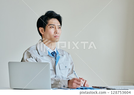 A young man in work clothes taking notes 128753604