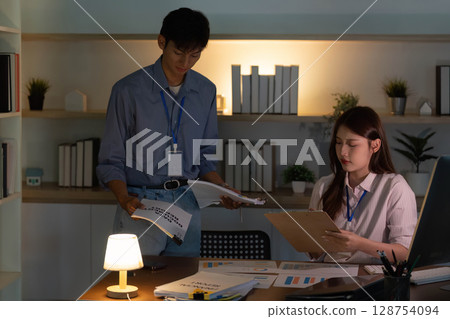 Office Dynamics. Colleagues discussing project details with documents in hand. 128754094