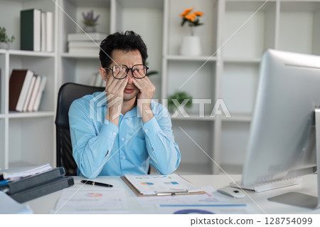 Tired professional overcomes hard work challenges at office desk detailed analysis business environment introspective viewpoint Tired professional overcomes hard work challenges at office desk detailed analysis business environment introspective viewpoint 128754099