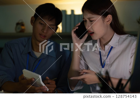 Team Collaboration. Young woman discussing with colleague on phone in modern office. 128754143