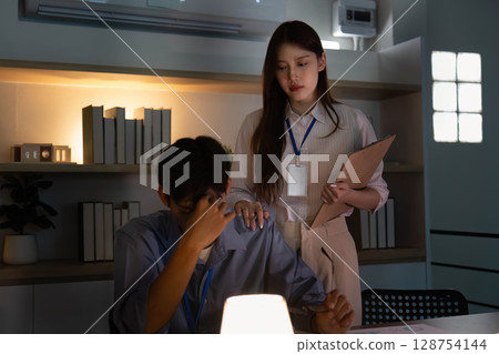 Supportive colleague comforting a stressed coworker in the office 128754144