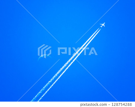 A scene of the moon floating in the blue sky with a contrail stretching out A scene of the moon floating in the blue sky with a contrail stretching out 128754288
