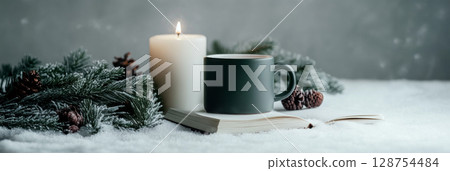 Lit candle and cup on book with pine branch for cozy Christmas festive winter setting 128754484