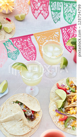 Cinco de Mayo celebration with tacos, drinks, and colorful decorations, food background 128754799