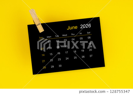June 2026 black calendar with wooden clip on yellow color background. 128755347