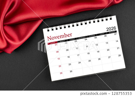 November 2026 Monthly desk calendar with red silk on black color leather background. 128755353