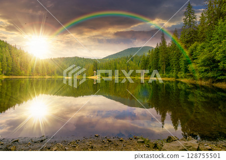 remote mountain landscape with forest lake in summer at sunset. travel nature background in evening light scenic view of coniferous trees reflection in water under the rainbow 128755501