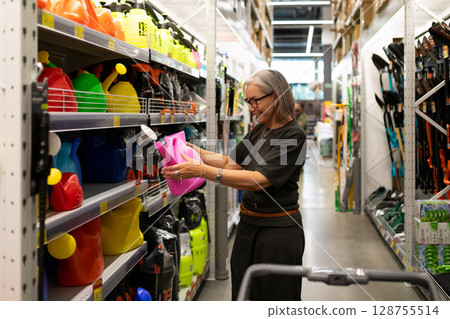 Middle-aged woman shopping for home and garden supplies in a large retail store during a casual day 128755514
