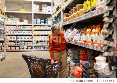 Middle-aged woman shopping in a modern home improvement store exploring various aisles including Middle-aged woman shopping in a modern home improvement store exploring various aisles including 128755565
