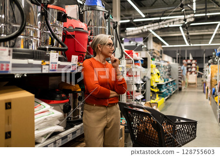 Woman choosing products in a hypermarket while exploring different departments for home essentials 128755603