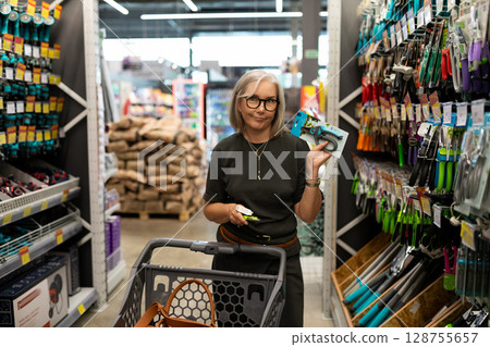 Middle-aged woman shopping in a large home improvement store with diverse products for her home and Middle-aged woman shopping in a large home improvement store with diverse products for her home and 128755657