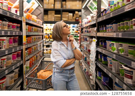 Shopping experience of a middle-aged woman in a modern construction hypermarket showcasing diverse Shopping experience of a middle-aged woman in a modern construction hypermarket showcasing diverse 128755658