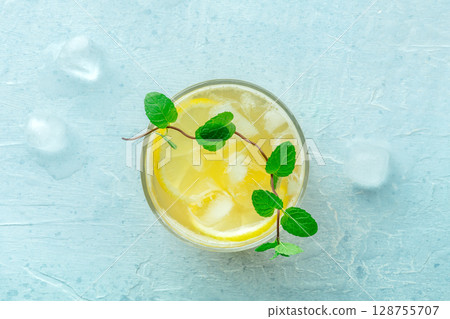 A glass of fresh lemonade, a mocktail with lemon juice, on a blue background A glass of fresh lemonade, a mocktail with lemon juice, on a blue background 128755707