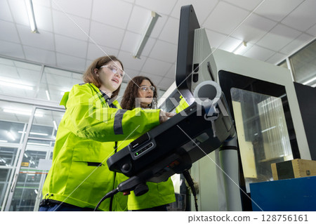 women engineer using computer control panel cnc machine at workshop. technician Female control automated machine process programming cnc machine at industry manufacturing. heavy industrial. 128756161