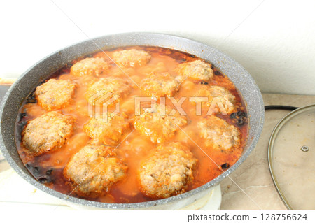 Meatballs in red tomato sauce cooking in a pan close-up 128756624