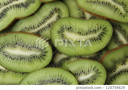 Kiwi close-up. The background is green of kiwi slices with black seeds. Natural background Kiwi close-up. The background is green of kiwi slices with black seeds. Natural background 128756629