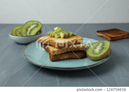 Healthy snack breakfast with toast and kiwi fruits on a plate on a gray background with space for text copyspace 128756630
