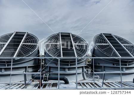 Cooling fans are installed on rooftop of large commercial building. Maintaining air circulation and temperature control. Tower air chiller HVAC. 128757344
