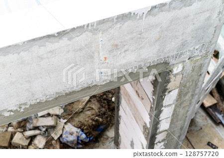 Closeup view of concrete beam on wall during house renovation. messy demolition phase of construction site shows chaos of building improvement 128757720