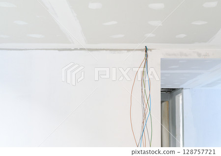 During interior renovation new gypsum board ceiling is installed showcasing smooth edges Building improvements include plastering ceilings where electrical wire preparation is complete 128757721