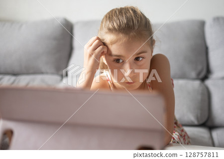 Young Girl Watching Tablet at home 128757811