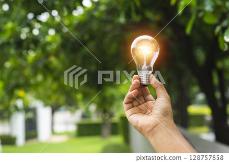 Hand holding Light bulb with light flare green nature background. eco innovation environmental and creative concepts. copy space banner. Hand holding Light bulb with light flare green nature background. eco innovation environmental and creative concepts. copy space banner. 128757858