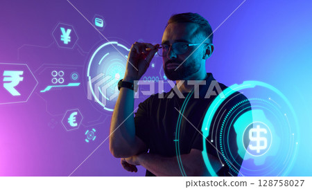 Man adjusting glasses with digital currency interface around on purple neon 128758027