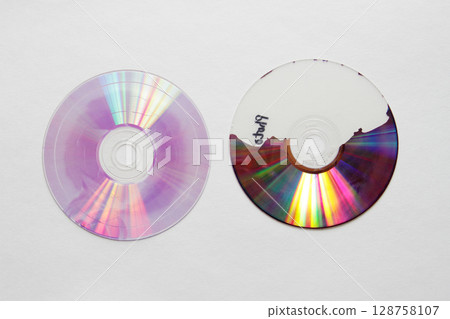 A DVD disc split in two with the recording layer half peeled off 128758107