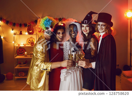 Diverse group of happy young men and women clinking glasses at a Halloween party 128758620