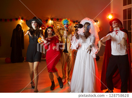 Group of friends in various Halloween spooky costumes pretend that they are walking dead. 128758628